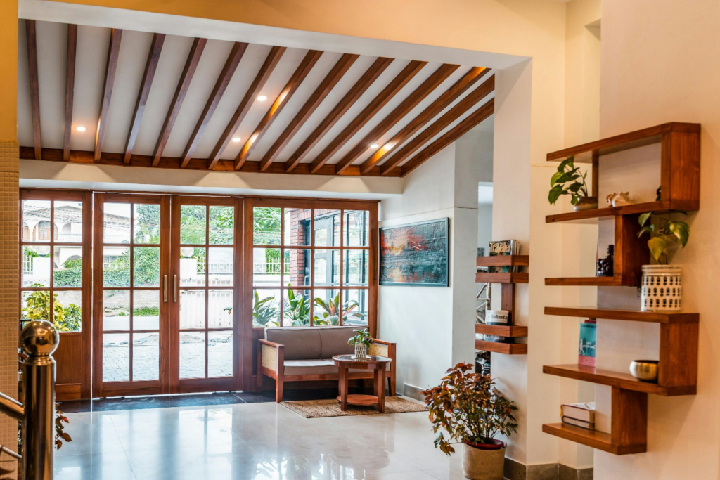 Bright and modern home interior with wooden ceiling beams and large glass doors leading to a lush outdoor space