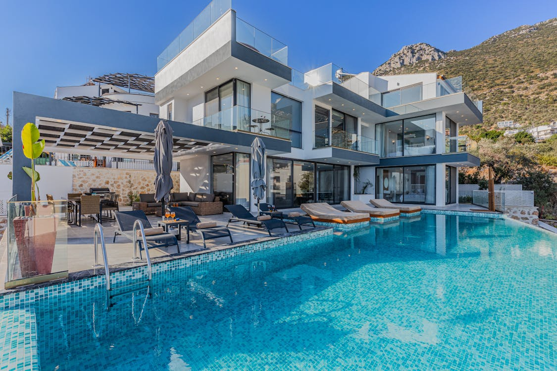 luxurious home with a big connected pool in the backyard with patio furniture