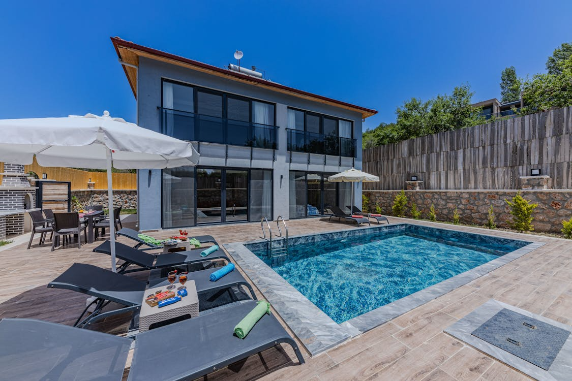 luxury home with glass doors and windows connected to a private backyard pool