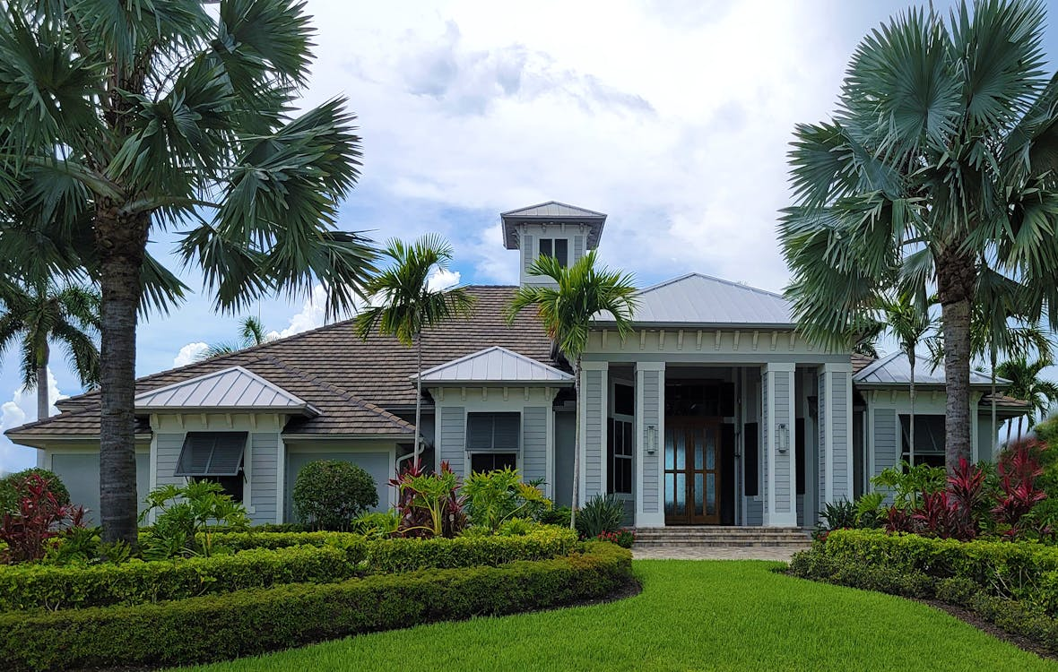 luxury house with palm trees around it, with a cloudy sky