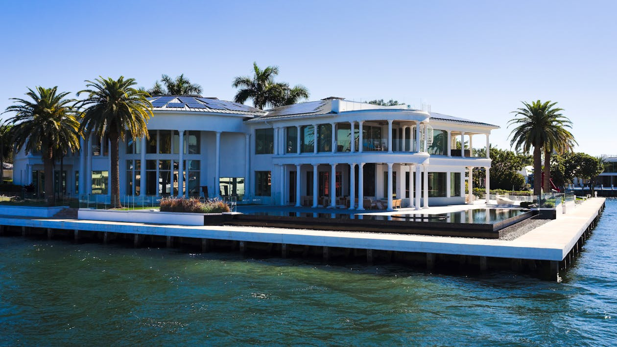 white luxury mansion built on a platform by the sea with palm trees